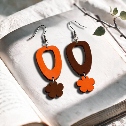 Orange and brown Luototar plywood earrings made in Finland, photographed on a vintage book in natural sunlight