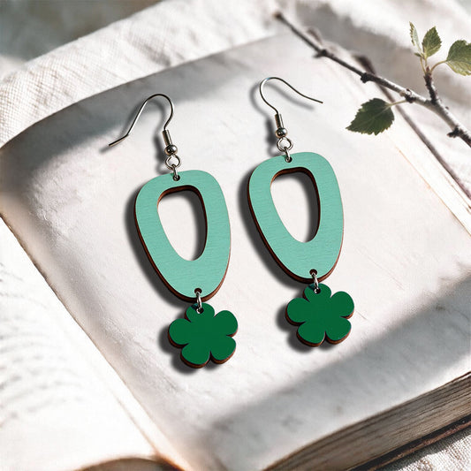 Turquoise and green Luototar plywood earrings made in Finland, photographed on a vintage book in natural sunlight