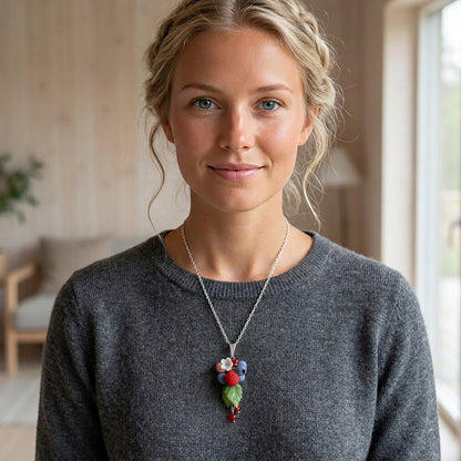 Blonde woman wearing the Berry Dance Necklace. Handmade necklace with hand-shaped berries and leaves, photographed in natural summer light. Handmade in Finland by byMinta.