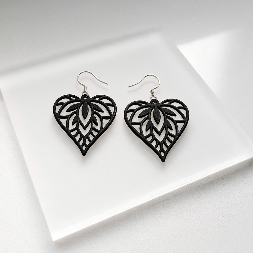 Black Mielilehti silicone earrings made in Finland, photographed on a vintage book in natural sunlight