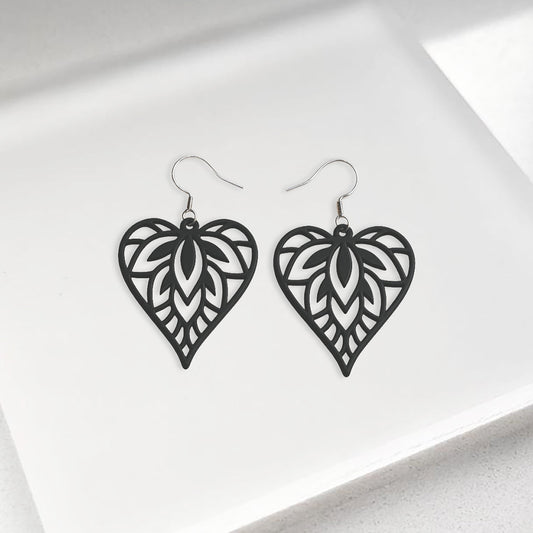 Black Mielilehti silicone earrings made in Finland, photographed on a vintage book in natural sunlight