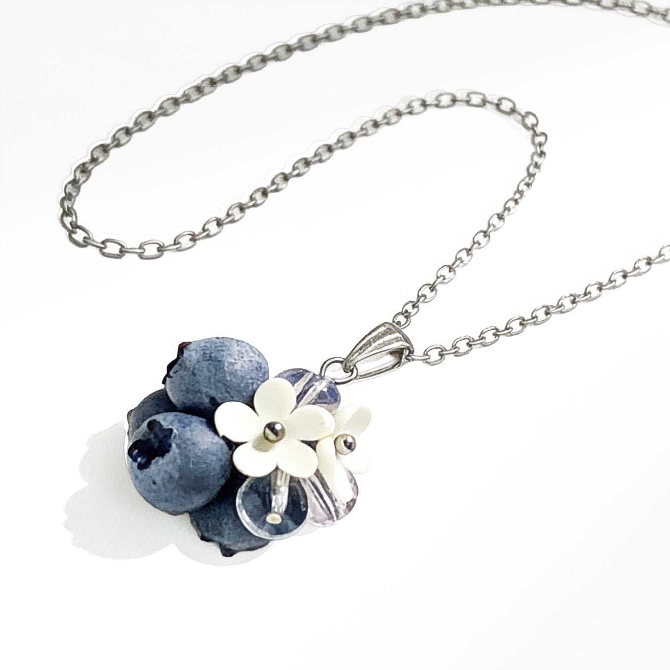 Handcrafted blueberry necklace with white flowers on a white background.