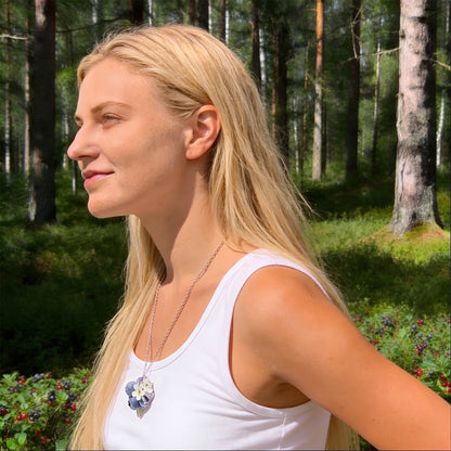 Blonde woman wearing the Blueberry Bouquet Necklace in a sunlit Nordic forest. Handmade necklace with blueberries and delicate flowers, photographed in natural summer light. Handmade in Finland by byMinta.