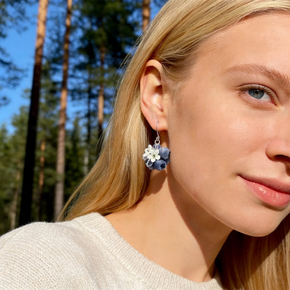 Blonde woman wearing Blueberry Bouquet Earrings in a sunlit Nordic forest. Handmade earrings inspired by the quiet beauty of summer berries.