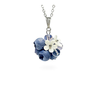 Handmade berry necklace featuring sculpted blueberries, translucent glass beads and delicate white flowers. Botanical statement jewelry on a fine chain against a clean white background, handcrafted in Finland.