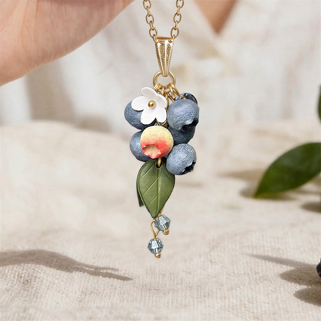 Blueberry Branch necklace handmade in Finland, featuring blueberries, an unripe berry, a flower and green leaves