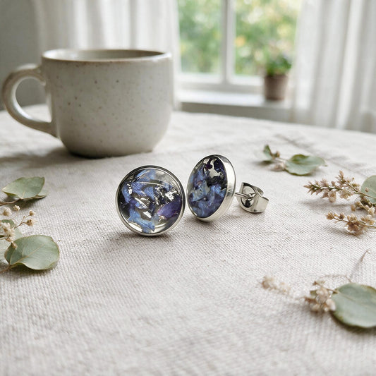Handmade resin stud earrings with real blue hydrangea petals in stainless steel settings on natural linen.