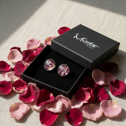 Handmade rose petal stud earrings displayed in a byMinta jewelry box, surrounded by real rose petals on natural linen in warm natural daylight.