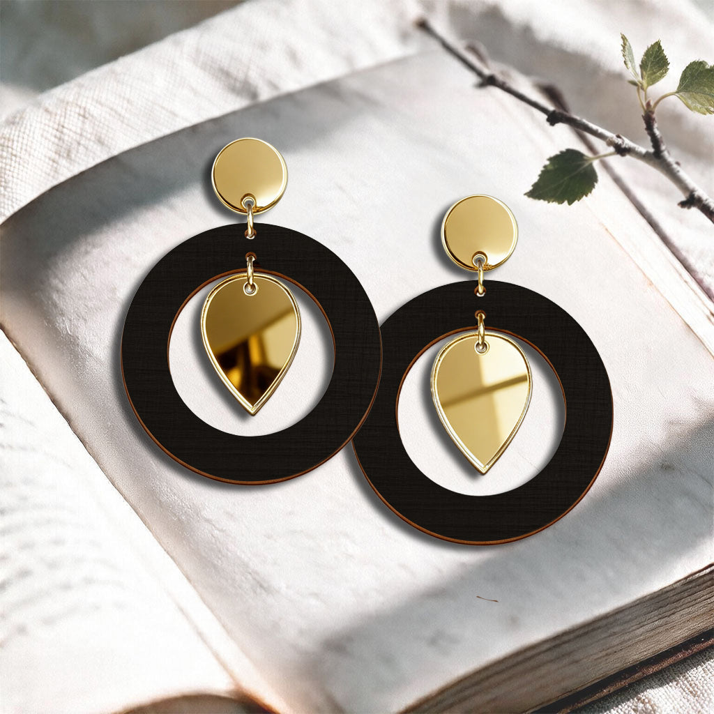 Black NiinMua birch plywood stud earrings with gold mirror acrylic drops, made in Finland, photographed on a light neutral background.