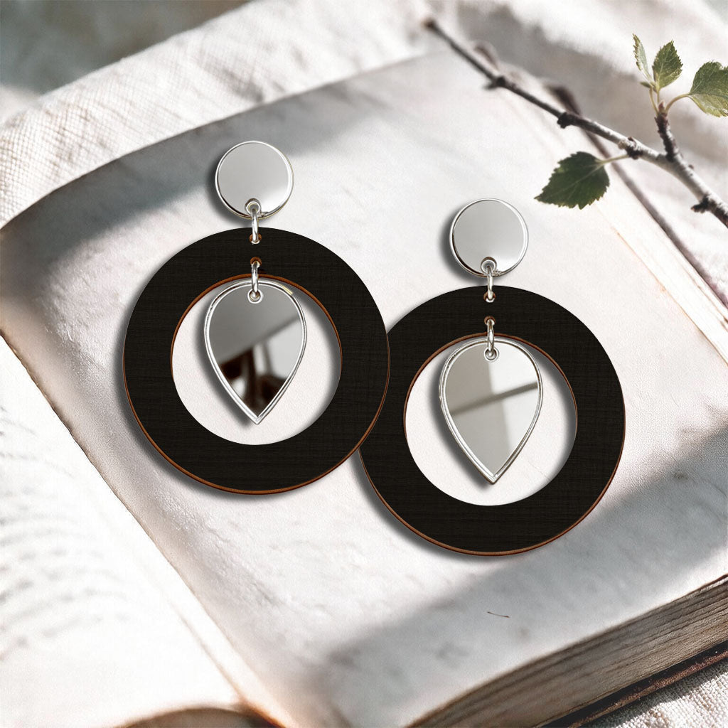 Black NiinMua birch plywood stud earrings with silver mirror acrylic drops, made in Finland, photographed on a light neutral background.
