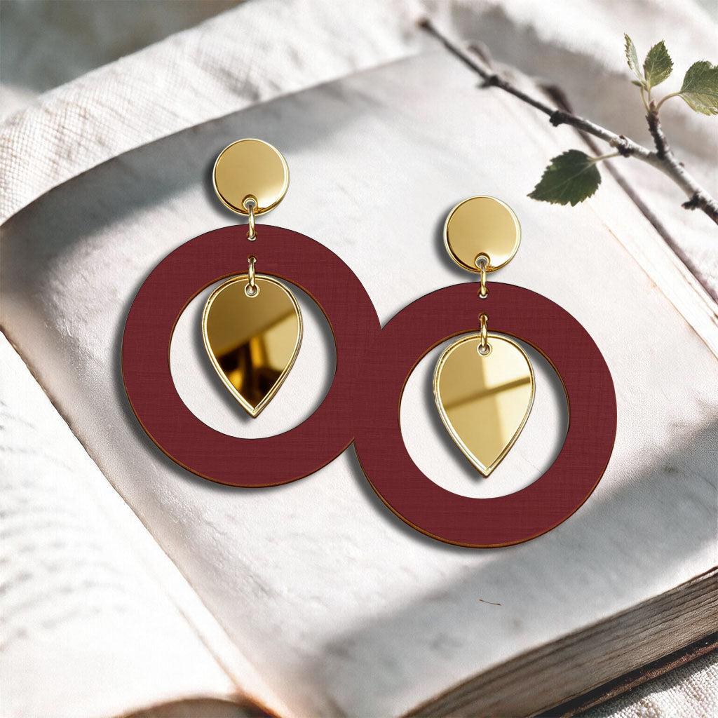 Rust NiinMua birch plywood stud earrings with gold mirror acrylic drops, made in Finland, photographed on a light neutral background.