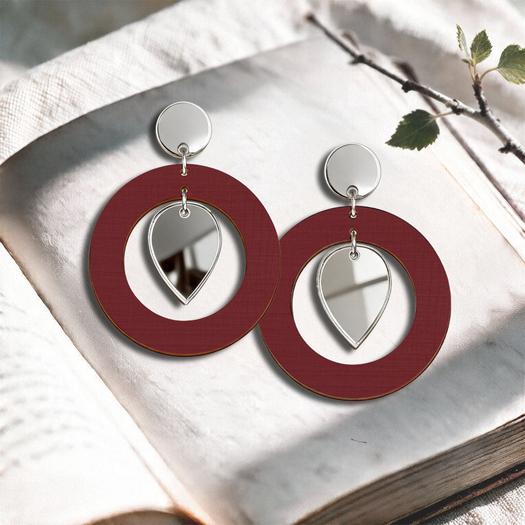 Rust NiinMua birch plywood stud earrings with silver mirror acrylic drops, made in Finland, photographed on a light neutral background.