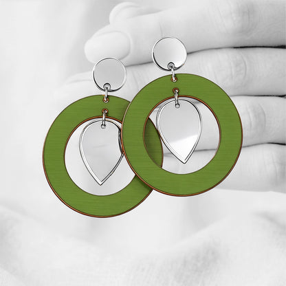 Green NiinMua plywood stud earrings with silver mirror acrylic teardrops, made in Finland, photographed against a black-and-white hand background.