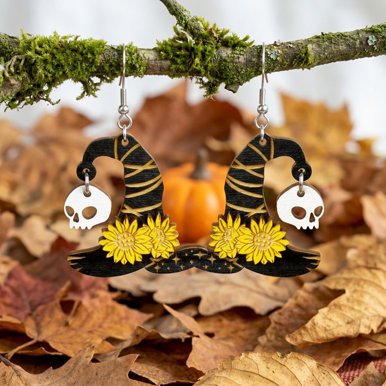 Witch Hat Earrings hanging from a moss-covered branch among autumn leaves.