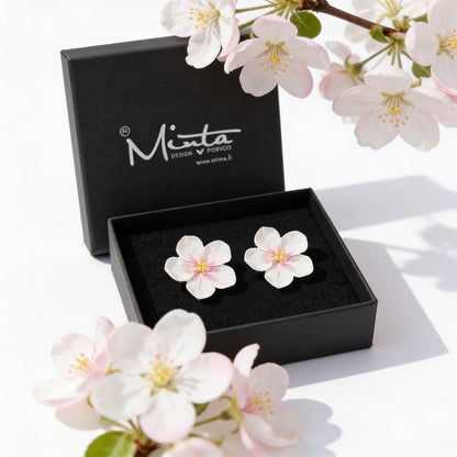 Apple blossom stud earrings by byMinta displayed in a jewelry box surrounded by soft blooming spring flowers in natural daylight.