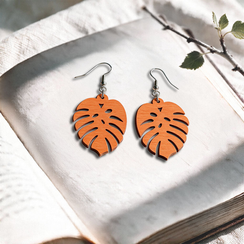 Orange Verdant plywood earrings made in Finland, photographed on a vintage book in natural sunlight