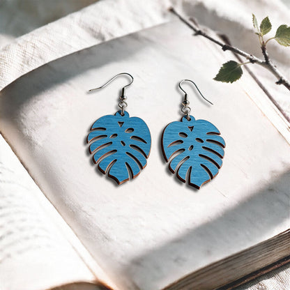 Skyblue Verdant plywood earrings made in Finland, photographed on a vintage book in natural sunlight