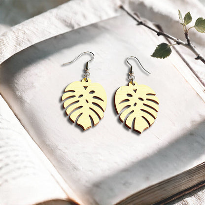 Vanilla Verdant plywood earrings made in Finland, photographed on a vintage book in natural sunlight