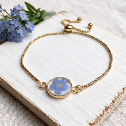 Adjustable gold plated bracelet featuring a real forget-me-not flower preserved under resin. Handcrafted in Finland.