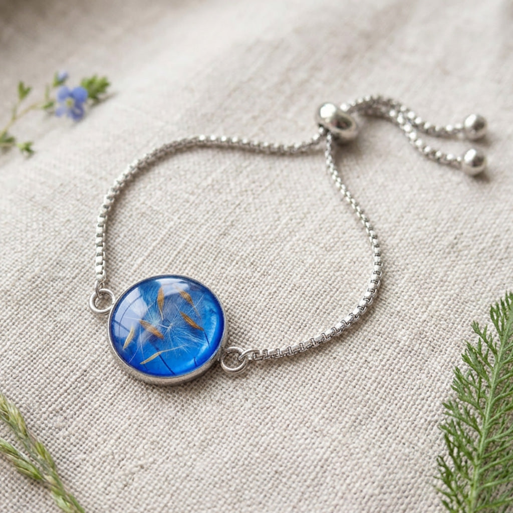 Handcrafted stainless steel bracelet featuring real dandelion seeds preserved in clear resin on natural linen. Made in Finland by byMinta.