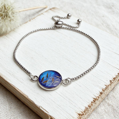 Handcrafted stainless steel bracelet featuring real dandelion seeds preserved in clear resin on natural linen. Made in Finland by byMinta.