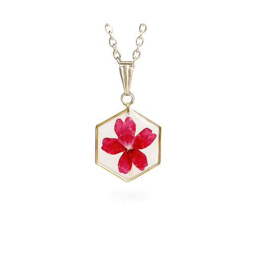 Handmade hexagon necklace with a real pressed red verbena flower preserved inside resin. Botanical jewelry with a white background, delicate gold-tone frame and fine chain on a clean white background, handcrafted in Finland.