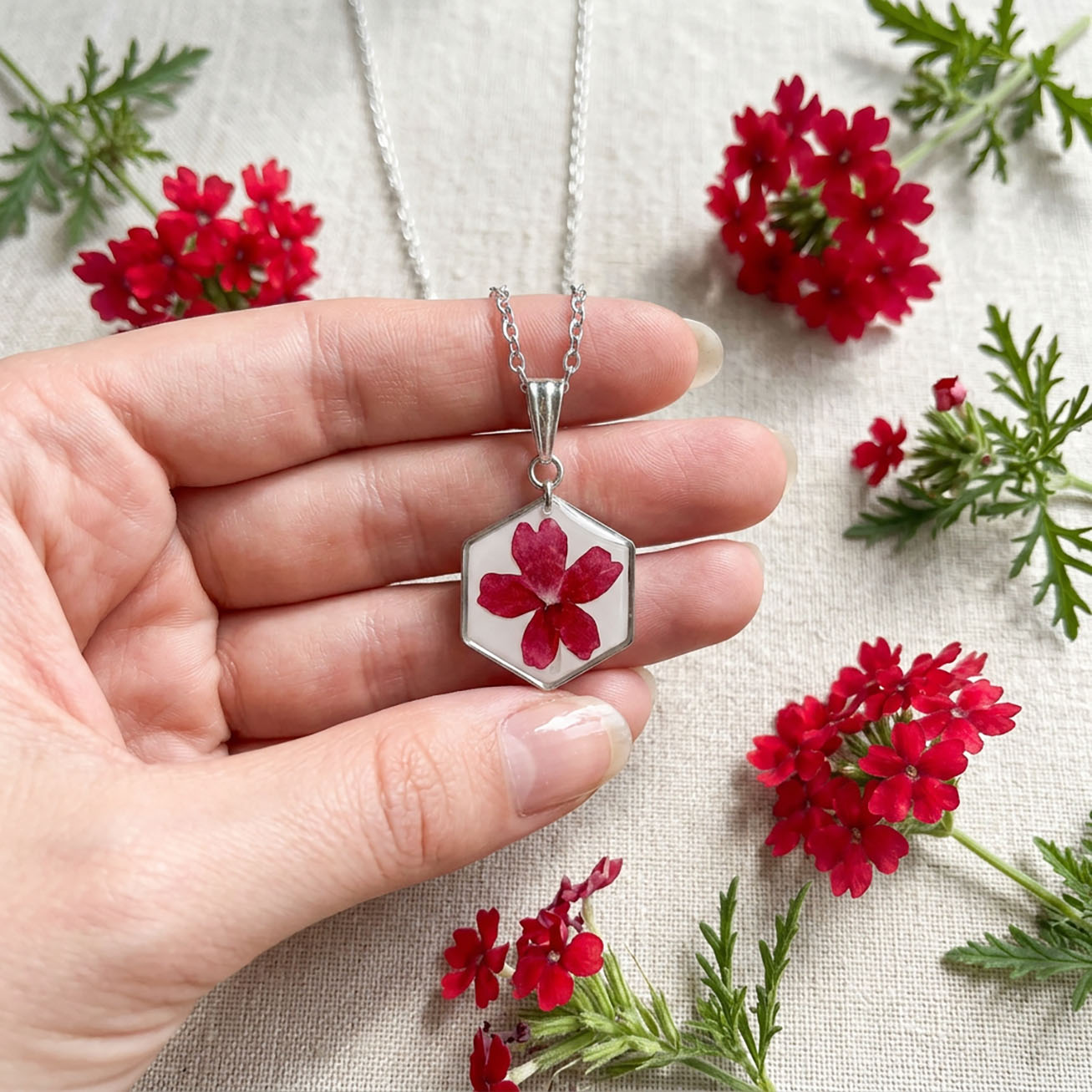 Close-up of real verbena flower pendant necklace with stainless steel chain and fresh red flowers