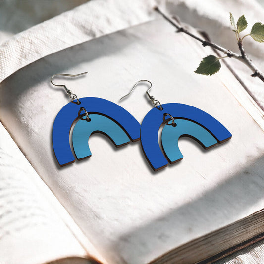 Blue an skyblue Riemukaari plywood earrings made in Finland, photographed on a vintage book in natural sunlight