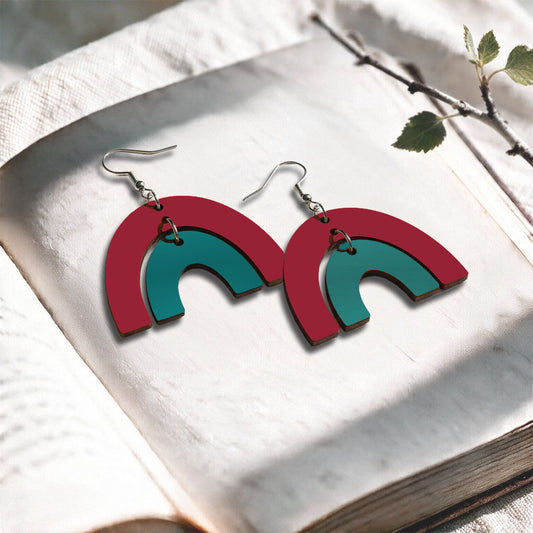 Rust and petrol Riemukaari plywood earrings made in Finland, photographed on a vintage book in natural sunlight