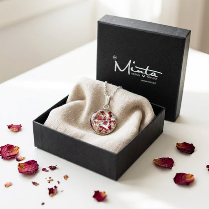 Handmade resin necklace with real rose petal fragments and silver leaf flakes presented in a gift box with linen fabric and rose petals.