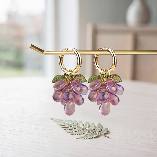 Plum Cluster Earrings with translucent purple glass beads, detachable charm and gold-plated huggie hoops on a soft linen background. Handcrafted in Finland.