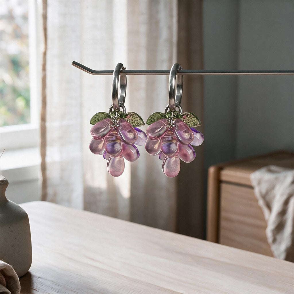 Plum Cluster Earrings hanging on a display stand with translucent purple glass beads and gold-plated huggie hoops. Handcrafted in Finland.