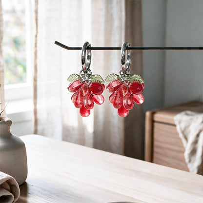 Red Currant Cluster Earrings hanging on a display stand with translucent red glass beads and gold-plated huggie hoops. Handcrafted in Finland.