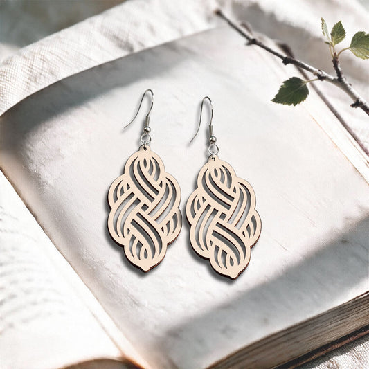 Nude Solmu plywood earrings made in Finland, photographed on a vintage book in natural sunlight