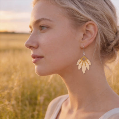 Handmade wooden leaf statement earrings worn by a Scandinavian woman in a golden meadow at sunset. Lightweight Finnish birch plywood earrings in warm natural light with soft Nordic summer atmosphere.