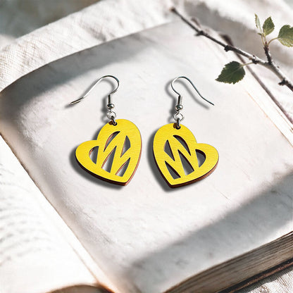 Yellow Heartbeat plywood earrings made in Finland, photographed on a vintage book in natural sunlight