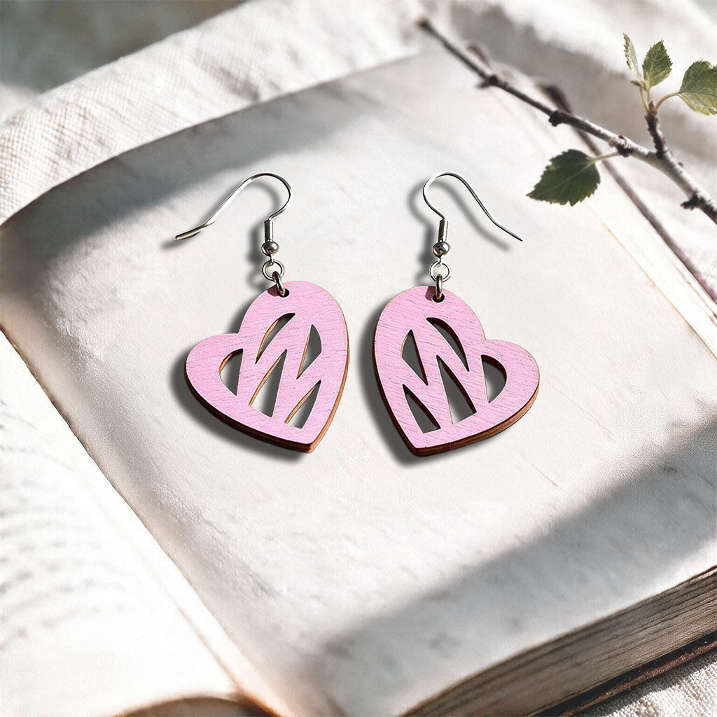 Mauve Heartbeat plywood earrings made in Finland, photographed on a vintage book in natural sunlight