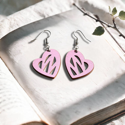 Mauve Heartbeat plywood earrings made in Finland, photographed on a vintage book in natural sunlight