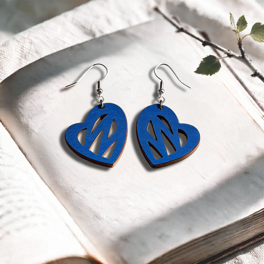 Blue Heartbeat plywood earrings made in Finland, photographed on a vintage book in natural sunlight