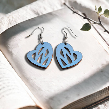 Light Blue Heartbeat plywood earrings made in Finland, photographed on a vintage book in natural sunlight