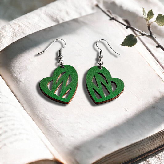 Green Heartbeat plywood earrings made in Finland, photographed on a vintage book in natural sunlight