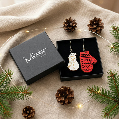 Christmas earrings presented in a gift box with pine branches, pinecones, and soft fairy lights, creating a cozy festive atmosphere. Handmade in Finland by byMinta.