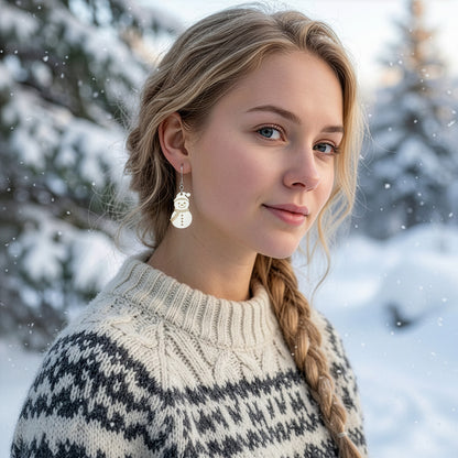 Blonde woman wearing the snowman earring in a snowy winter Finnish landscape, dressed in a warm Nordic knit sweater. Handmade in Finland by byMinta.