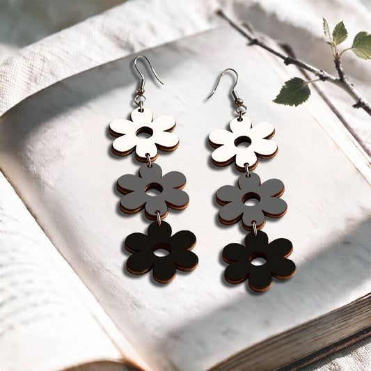 White, grey and black TriplaRetro plywood earrings made in Finland, photographed on a vintage book in natural sunlight