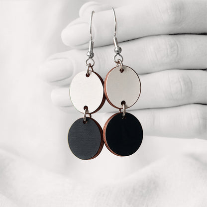 Black and white Tuplakupla duo plywood earrings handmade in Finland, featuring two round wooden pieces on stainless steel hooks