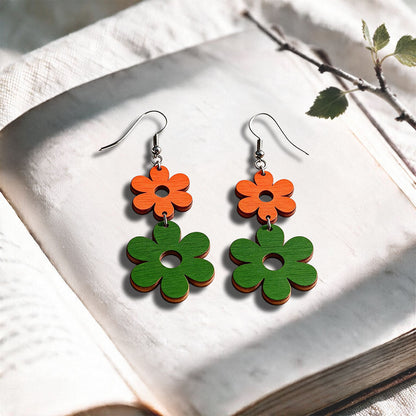 Green and orange Double Retro plywood earrings made in Finland, photographed on a vintage book in natural sunlight