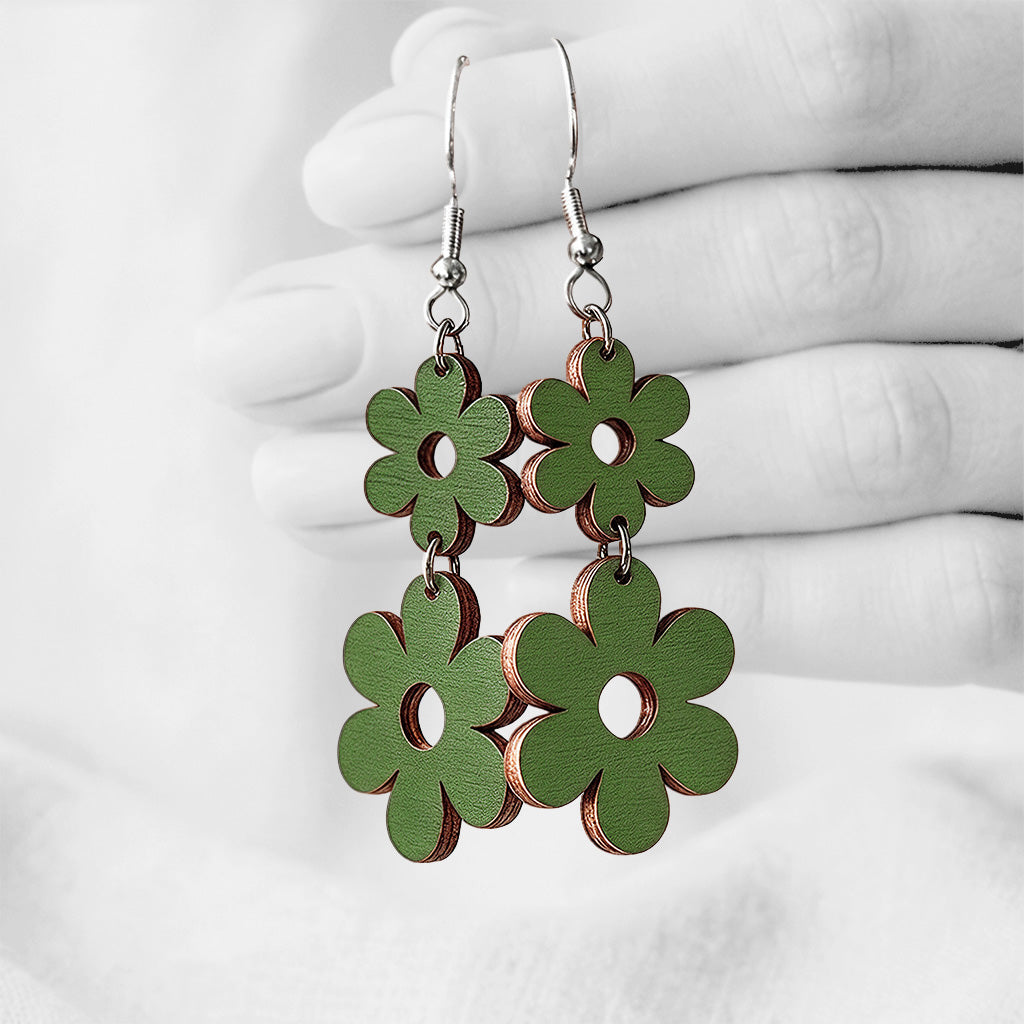Moss Green Double Retro plywood earrings made in Finland, photographed hanging from a hand in black and white against a softly blurred light background.