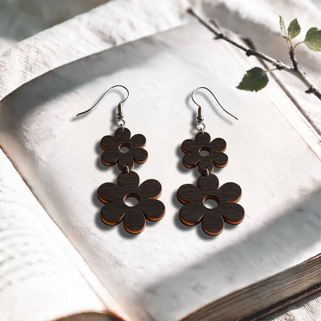 Black Double Retro plywood earrings made in Finland, photographed on a vintage book in natural sunlight