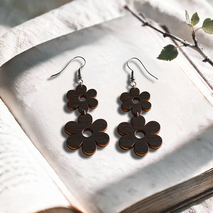 Black Double Retro plywood earrings made in Finland, photographed on a vintage book in natural sunlight