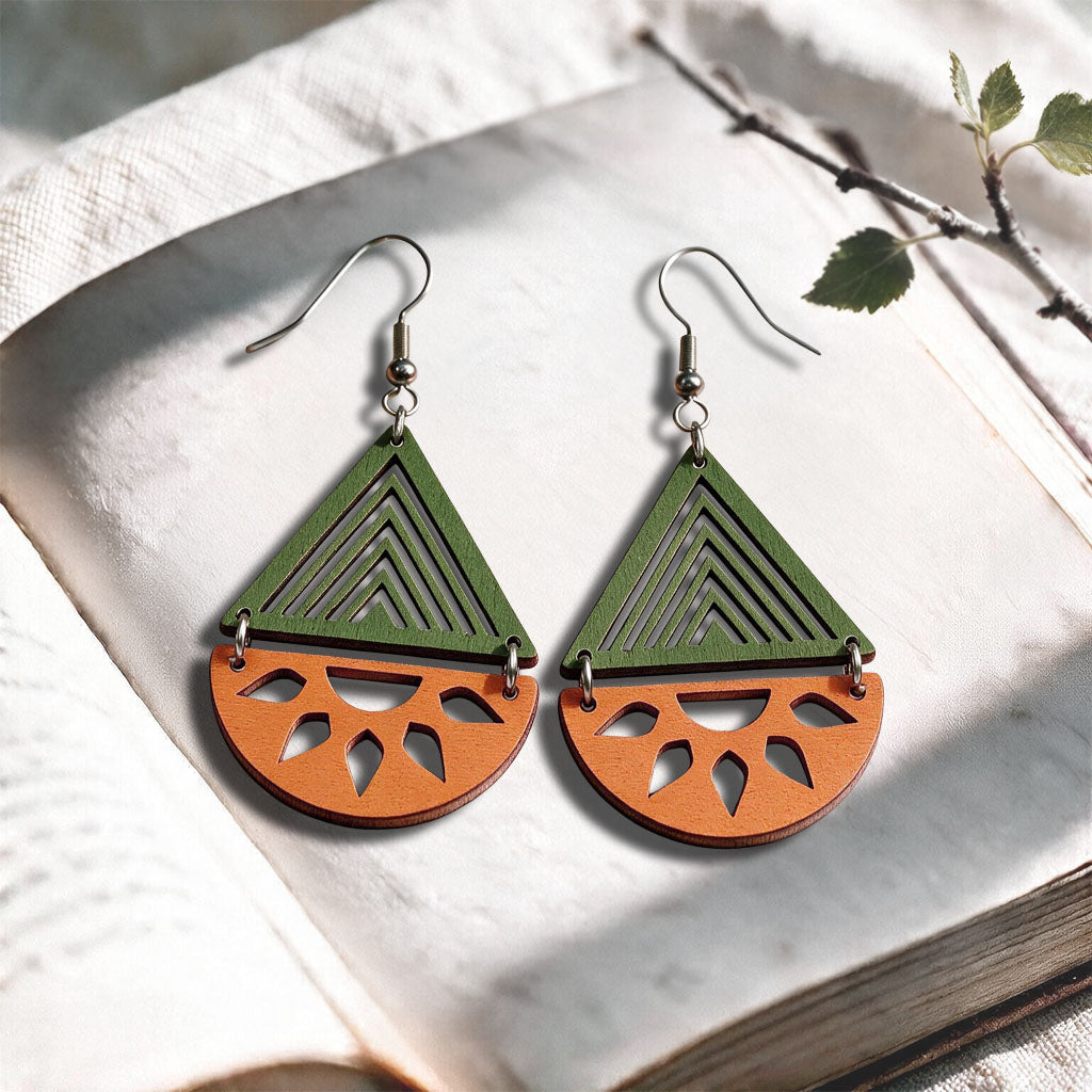 Orange and green Open Sea plywood earrings made in Finland, photographed on a vintage book in natural sunlight